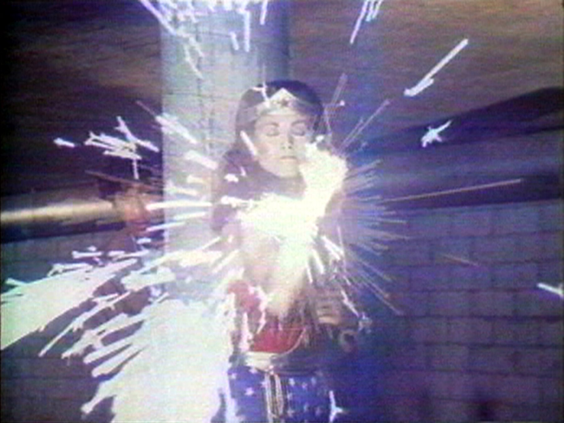 ダラ・バーンバウム「Technology/Transformation: Wonder Woman」：目を閉じ、両手から光を放つスーパーヒーロー。シリーズからの一場面