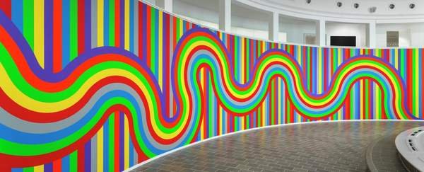 ソル・ルウィット「Wall Drawing #1136」：赤、黄、青、緑、橙、紫、灰の帯がうねる曲線となり、縦縞の上を走って3つの壁を覆う