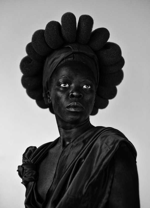 Zanele Muholi, Somnyama Ngonyama: chân dung tự chụp đen trắng độ tương phản cao, nghệ sĩ nhìn thẳng ống kính, đội đạo cụ làm từ vật dụng gia đình